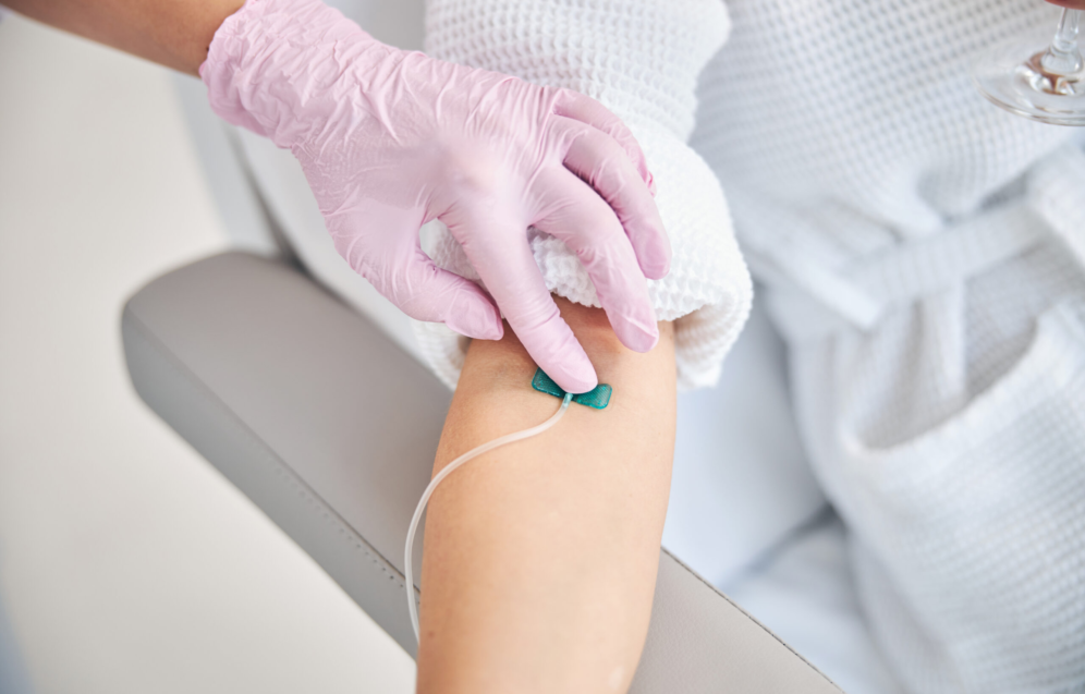 Cropped photo of a female patient lying in bed with a catheter in her vein