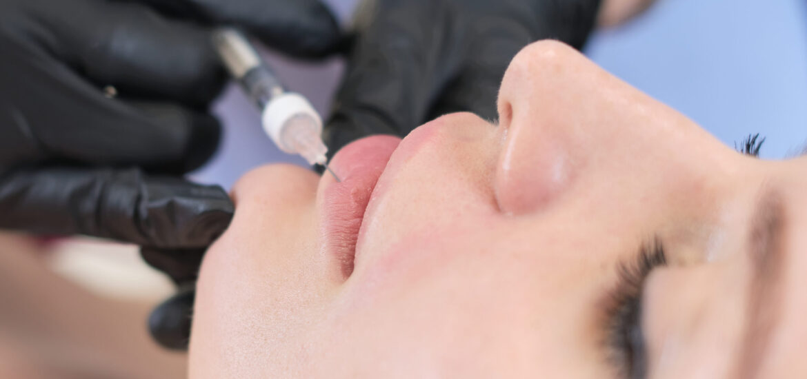 A cosmetologist carefully injects a client's lips. Enhancements come with both benefits and risks
