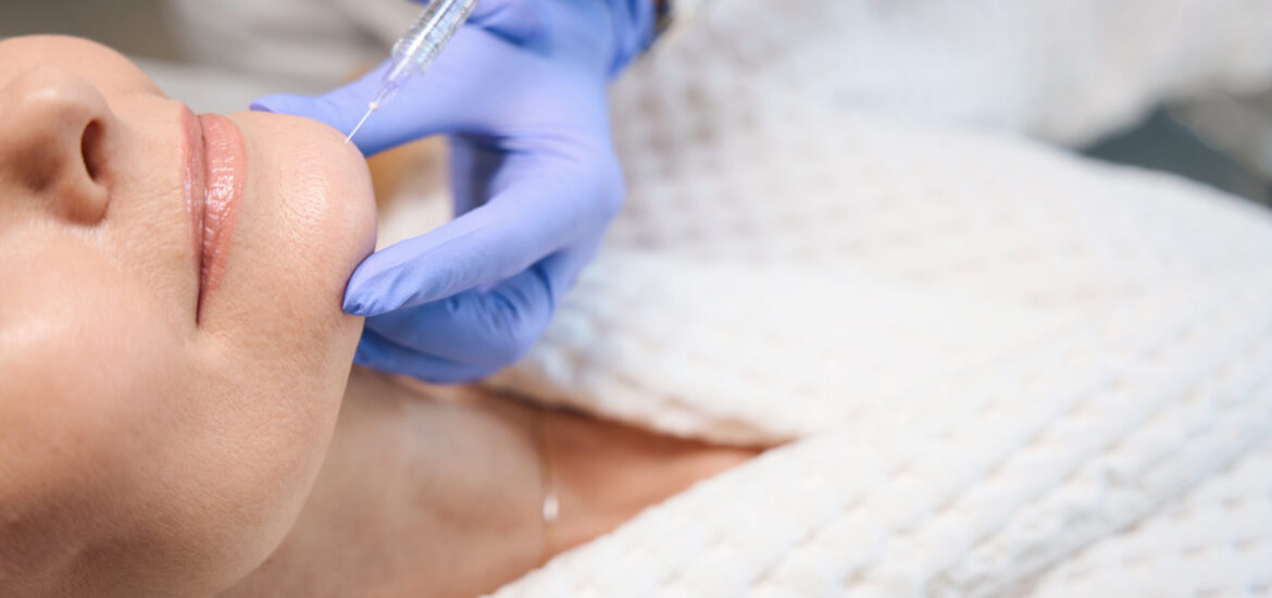 Close up of cosmetologist hands making injection for smoothing wrinkles on mature woman face in beauty salon