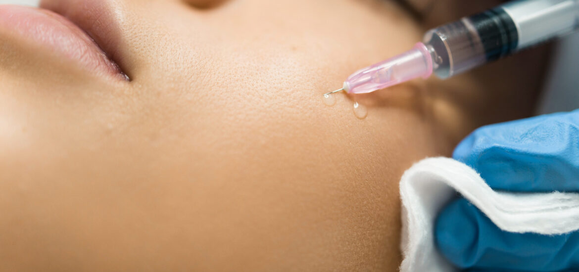 Close-up view of a beautician hands injecting hyaluronic acid into a patient's cheek