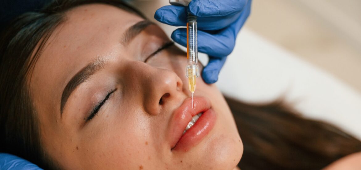 Cosmetologist does injection for lips augmentation. Women's cosmetology in the beauty salon.