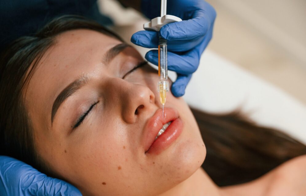 Cosmetologist does injection for lips augmentation. Women's cosmetology in the beauty salon.