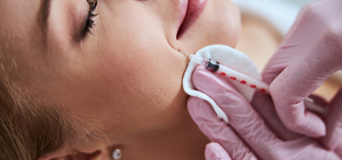 Cropped photo of a dermatologist in sterile gloves carrying out the professional facial rejuvenation treatment