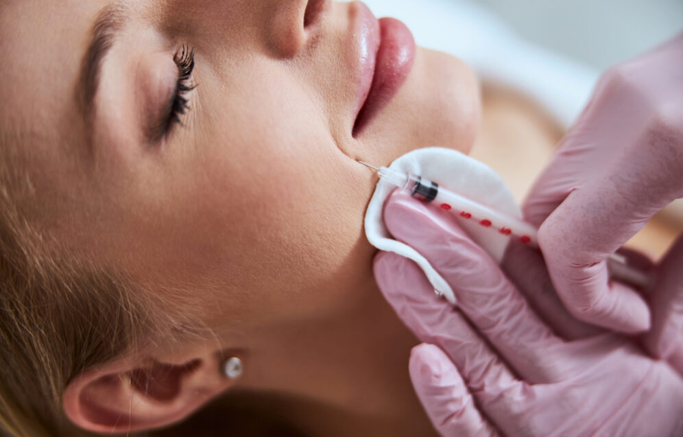 Cropped photo of a dermatologist in sterile gloves carrying out the professional facial rejuvenation treatment