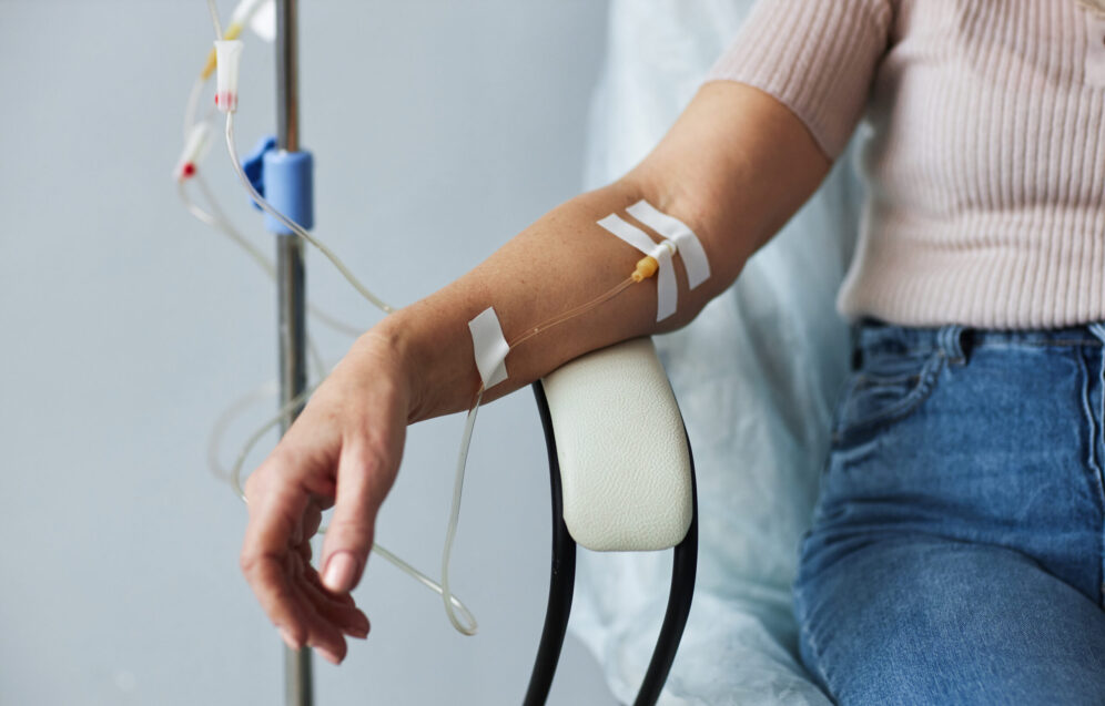 Closeup of female hand with IV drip infusion in treatment session at hospital, copy space