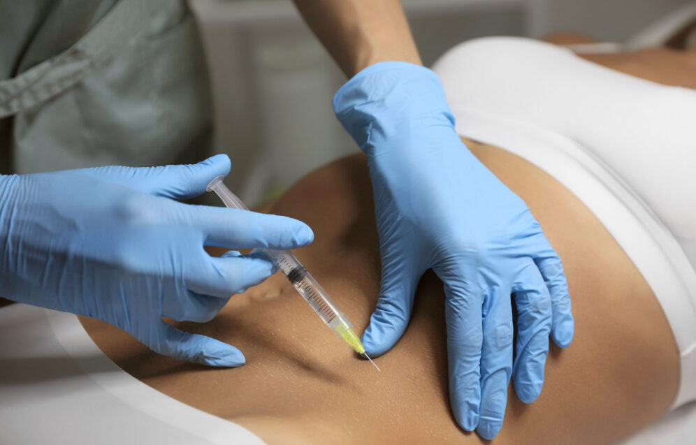 Young woman getting belly injection in salon, closeup